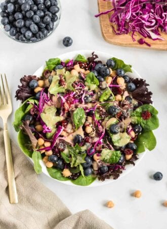 Overhead view of a colourful salad with greens, cabbage and blueberries.