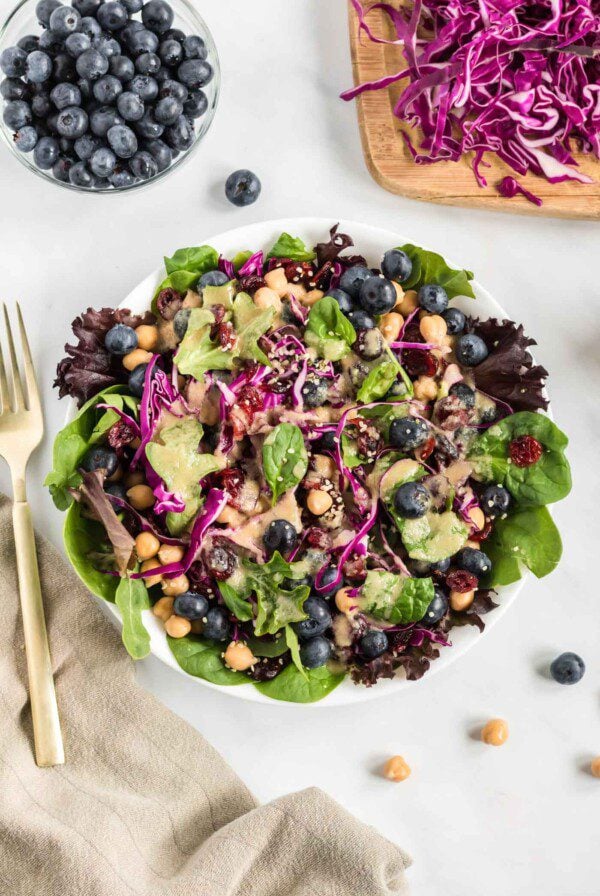 Overhead view of a colourful salad with greens, cabbage and blueberries.