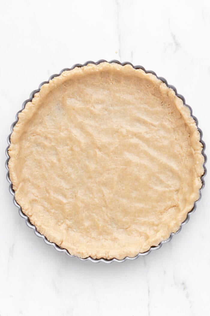 An unbaked pie crust pressed into a tart pan.