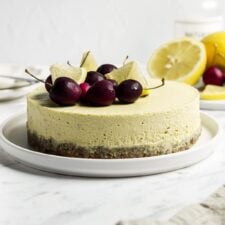 Raw vegan lemon cheesecake topped with cherries and lemon slices on a plate.