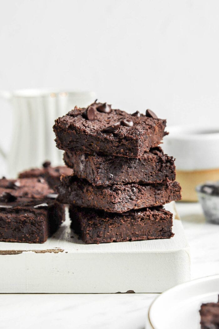 Stack of 3 black bean brownies on a cutting board.