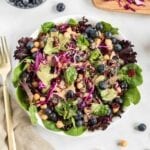 Overhead view of a colourful salad with greens, cabbage and blueberries.