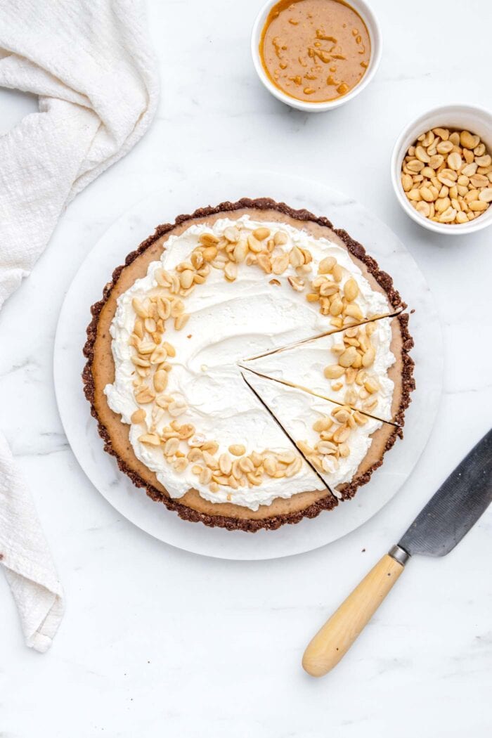 Overhead view of a peanut butter pie cut into two slices. Knife rests beside pie.