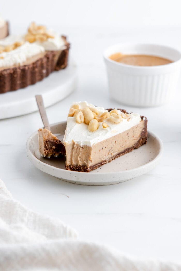 Slice of peanut butter pie on a plate with a bite taken from it.