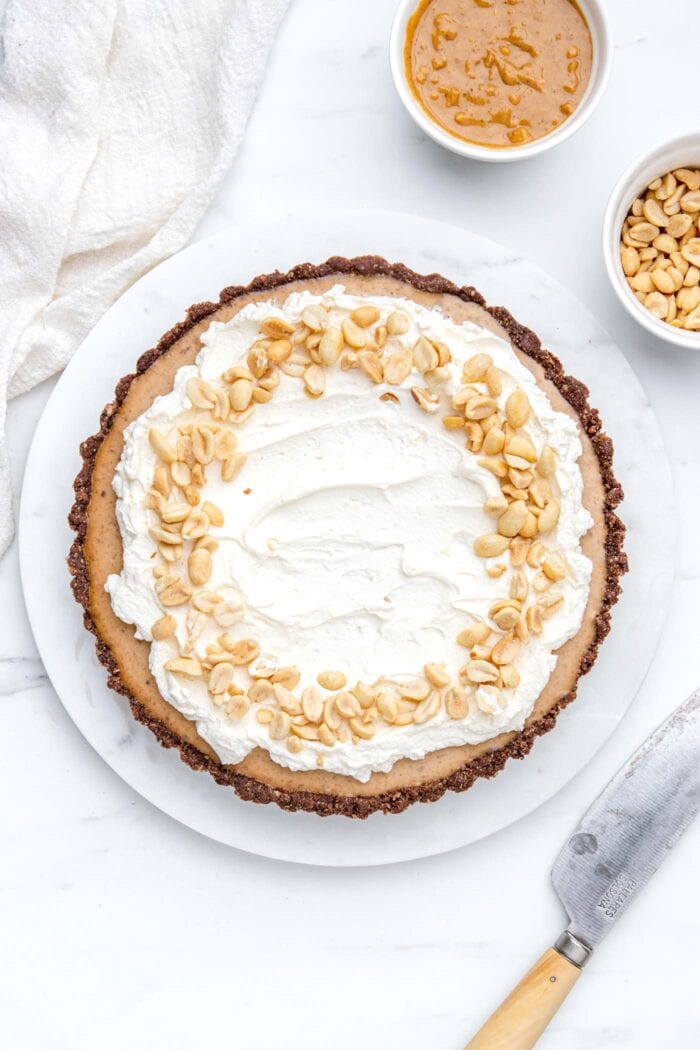 Overhead view of a peanut butter pie topped with whipped cream and peanuts.