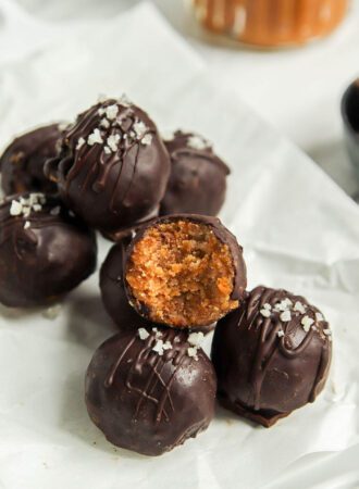 Stack of pumpkin truffles on a plate. One has a bite out of it showing texture inside.