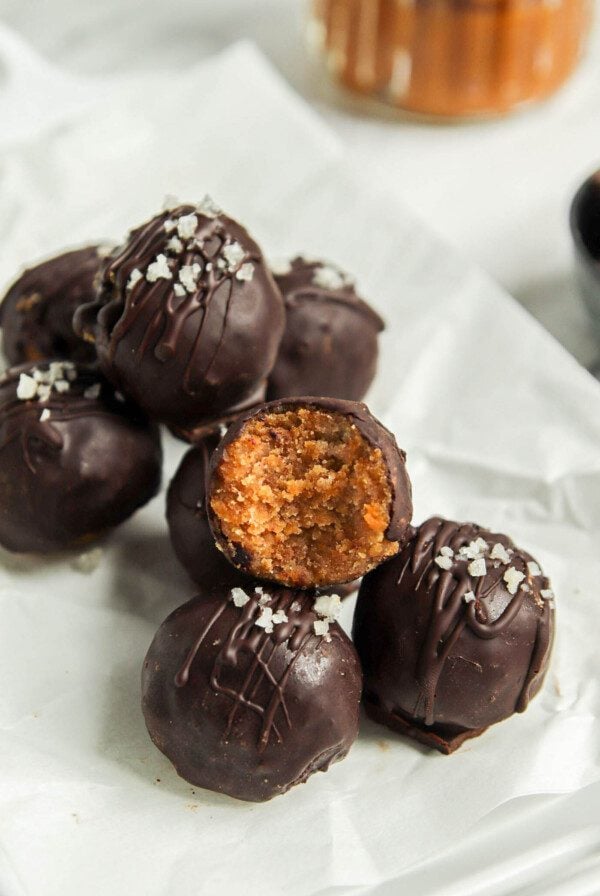 Stack of pumpkin truffles on a plate. One has a bite out of it showing texture inside.