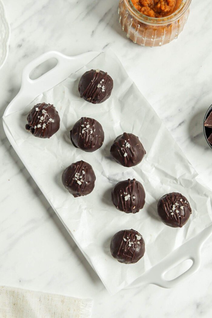 Chocolate pumpkin balls on a parchment paper-lined tray.