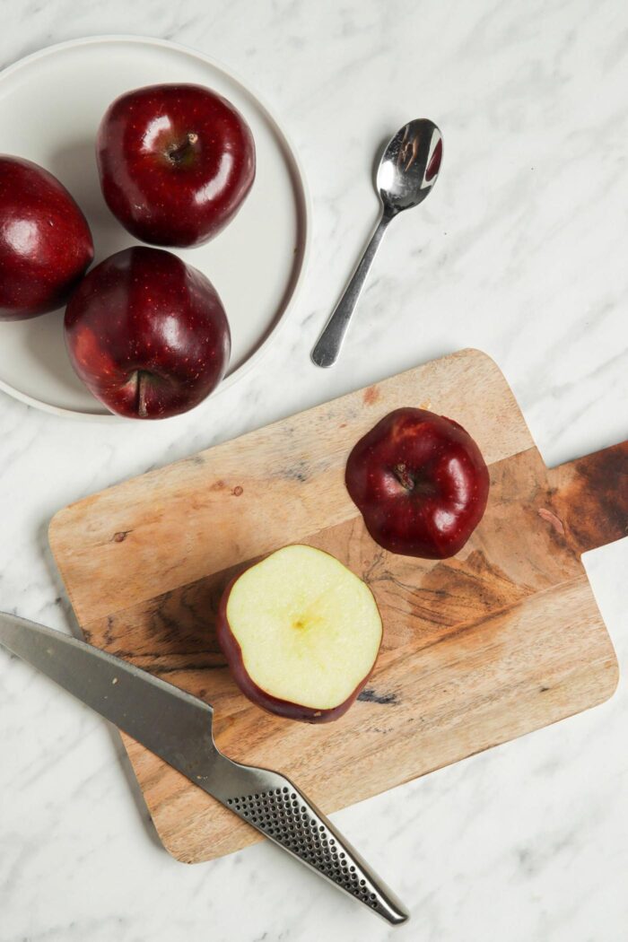 Apple on a cutting board with the top cut off of it.