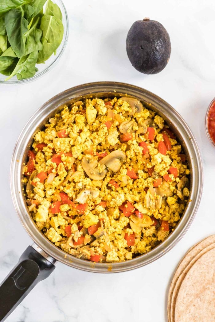 Tofu and vegetable scramble cooking in a pan.