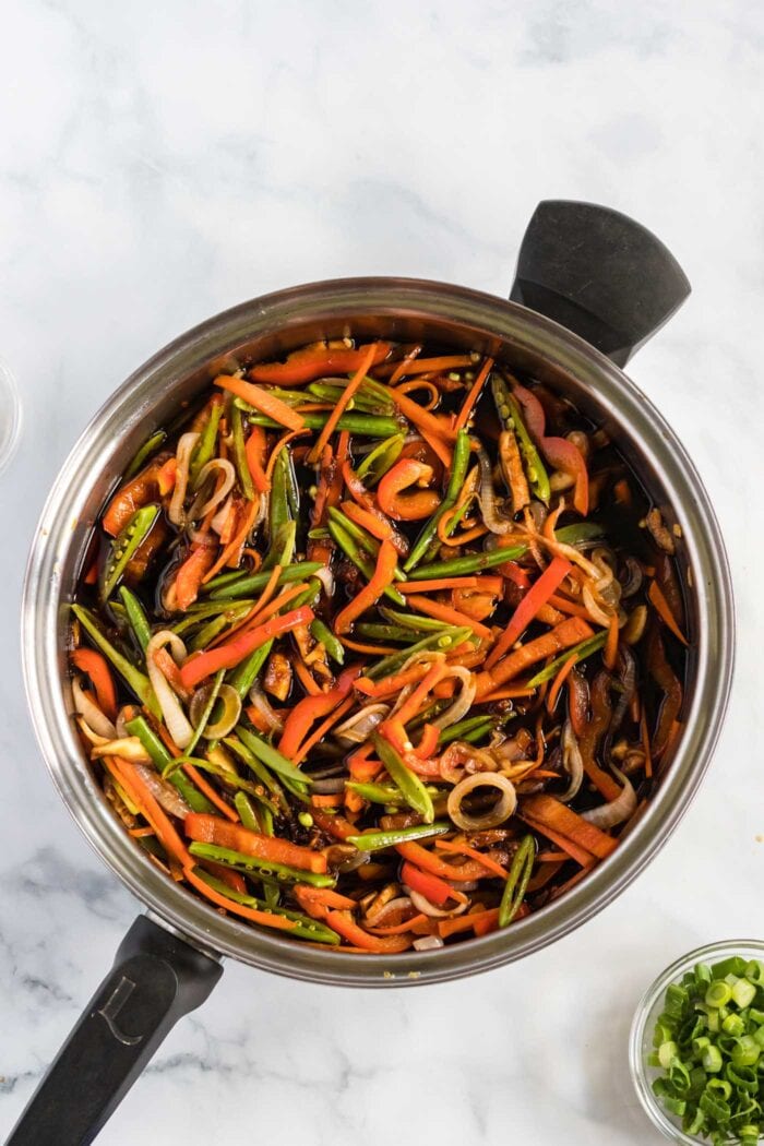 Stir fried vegetables cooking in a large frying pan.