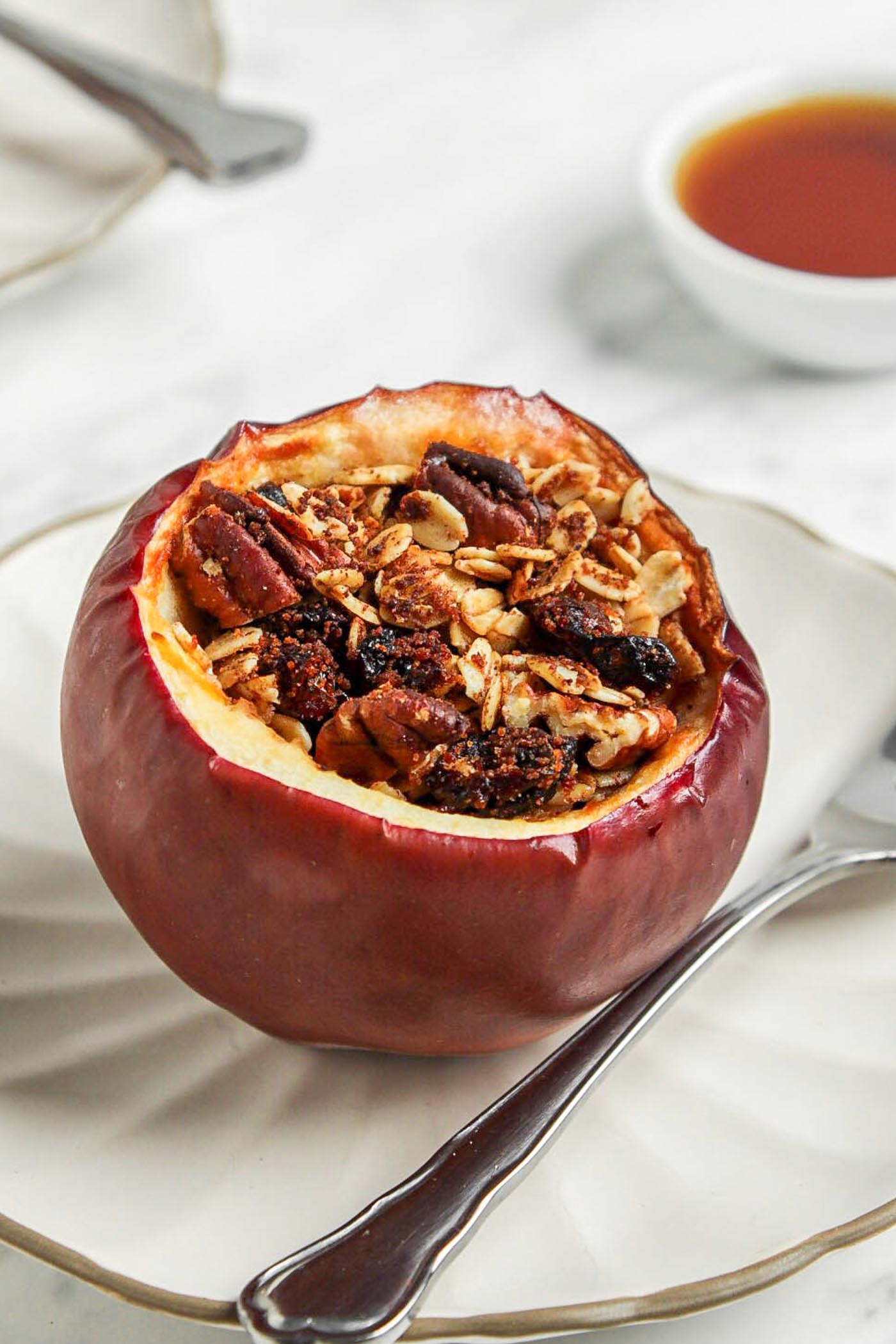 Baked stuffed apple on a small plate with a spoon.