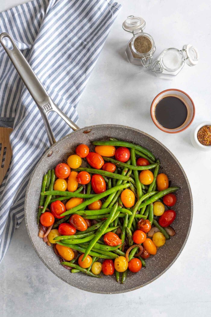 Green beans, onions and tomatoes in a skillet.