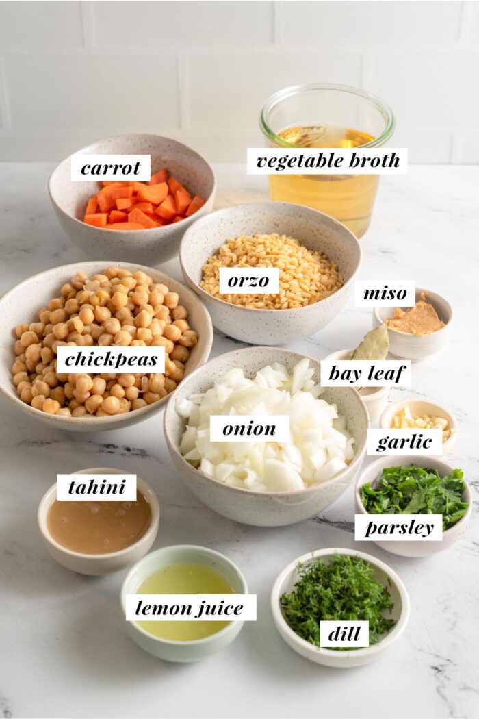 Visual list of ingredients for making a lemon orzo soup with chickpeas, spinach, onion and carrot.