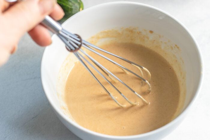 Whisking a creamy sauce in a small bowl.