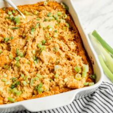 Close up of creamy buffalo dip in a white ceramic baking dish.