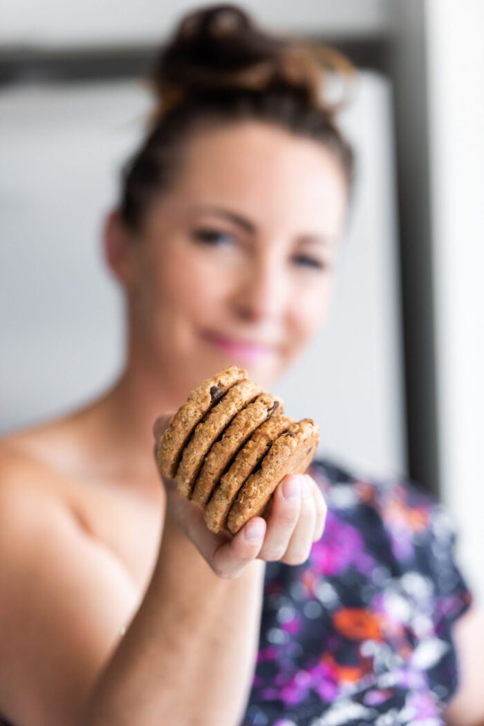 Woman holding 4 cookies towards the camera.