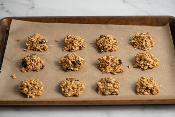 12 oatmeal cookies on a baking tray lined with parchment paper.
