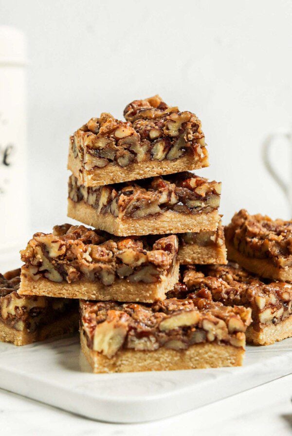 Close up of a stack of pecan pie bars on a cutting board.