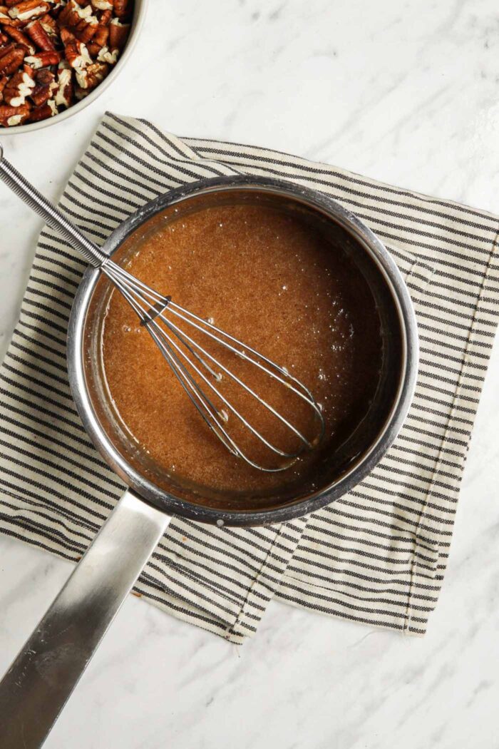 Thick, caramel mixture in a saucepan with a whisk.