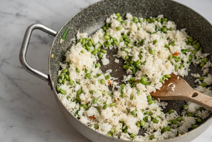 Rice and edamame cooking in a skillet.