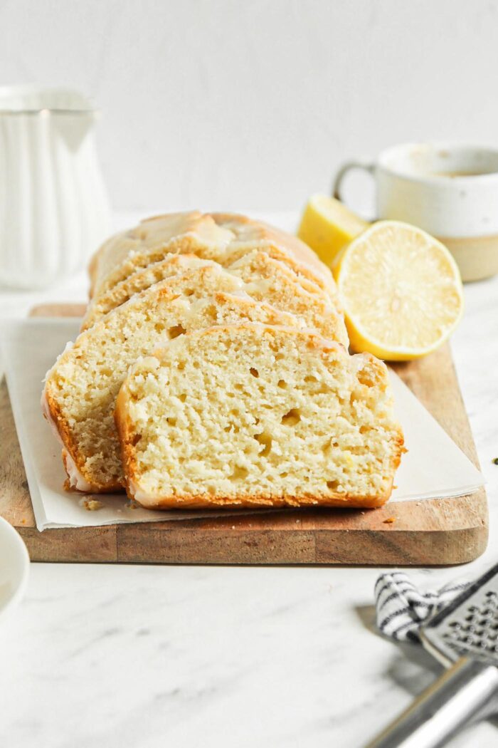 Sliced lemon loaf with icing on a cutting board.
