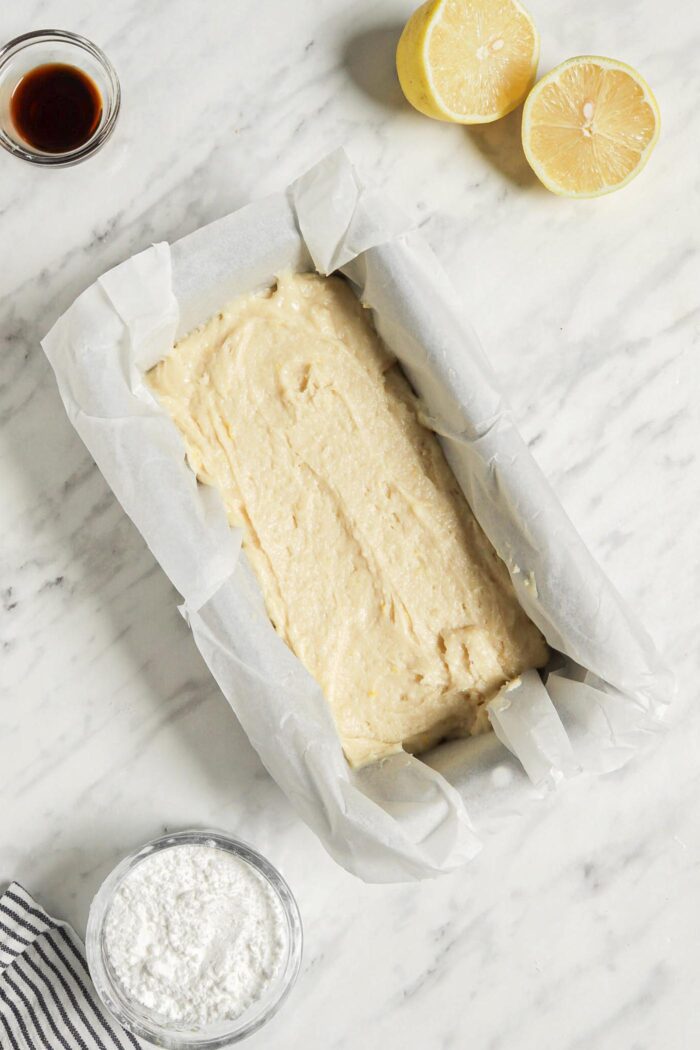 Unbaked lemon loaf cake in a loaf pan lined with parchment paper.