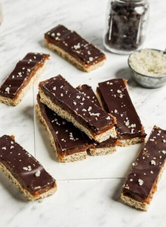 A number of homemade Twix candy bars on a marble surface lined with parchment paper.