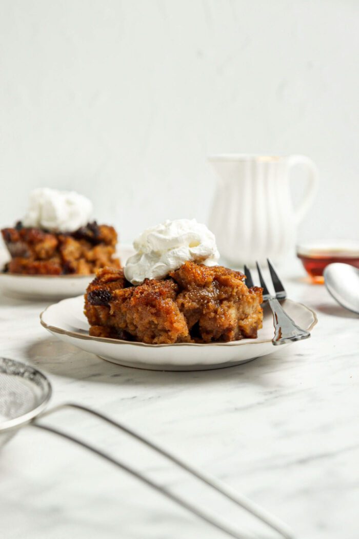 A slice of bread pudding topped with whipped cream on a plate.