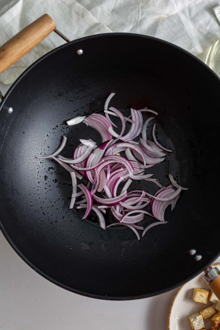 Thinly sliced onions cooking in a wok.