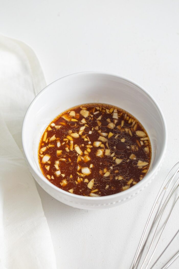Teriyaki sauce with small bits of garlic and ginger in a small bowl.