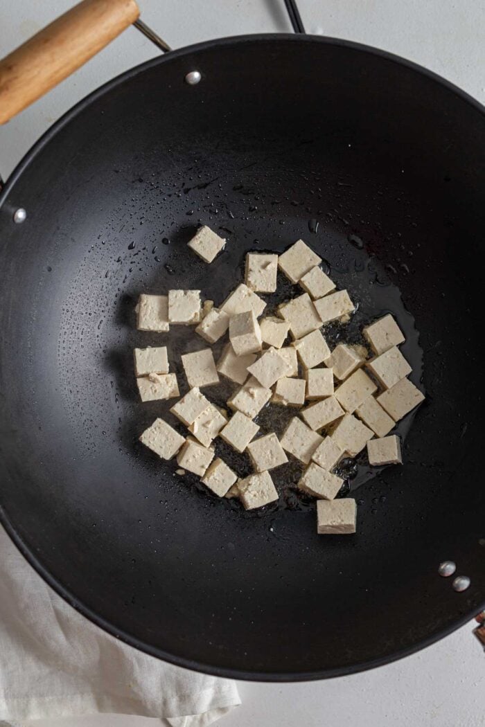 Cooking cubes of tofu in a hot wok.