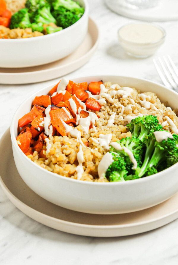 Healthy bowl with red lentils, quinoa, broccoli, carrot, squash and tahini sauce.