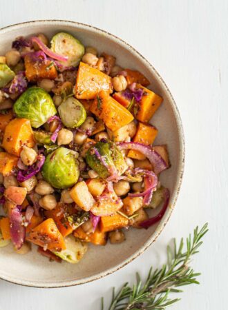Overhead view of a dish of chickpeas, sweet potato, Brussels sprouts, cabbage and red onion in maple dijon sauce.