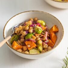 Small dish of chickpeas, sweet potato, Brussels sprouts, cabbage and red onion in maple dijon sauce.