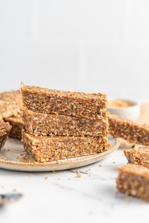 Stack of 3 homemade energy bars on a plate with more bars scattered around them.