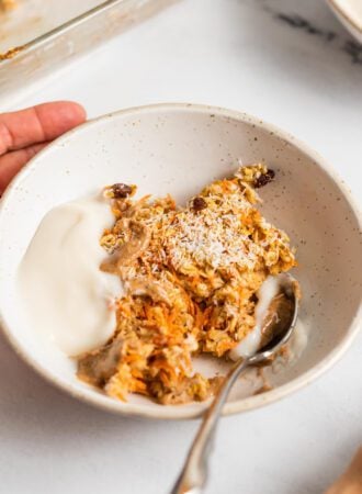 Bowl of carrot cake baked oatmeal topped with yogurt and almond butter.