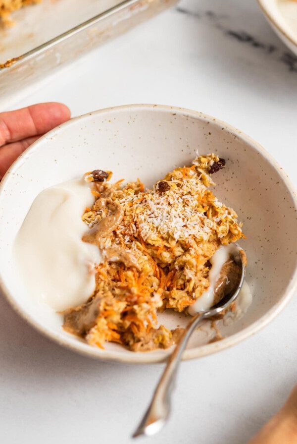 Bowl of carrot cake baked oatmeal topped with yogurt and almond butter.