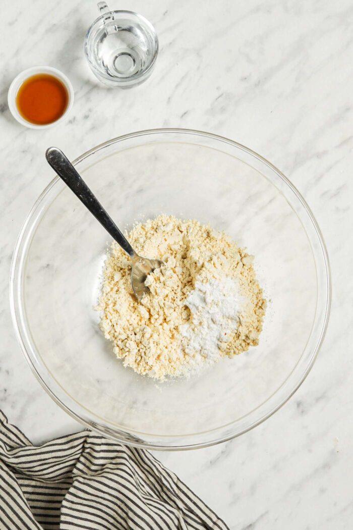 Baking powder, salt and chickpea flour mixed together in a glass mixing bowl.