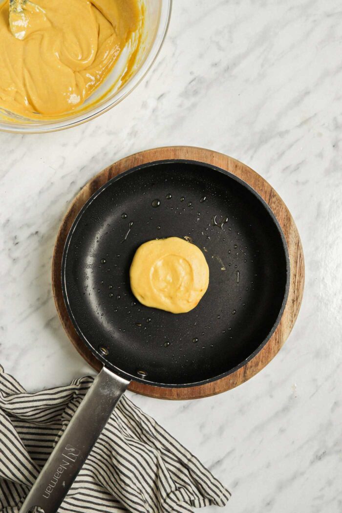 One chickpea flour pancake cooking in a hot skillet.