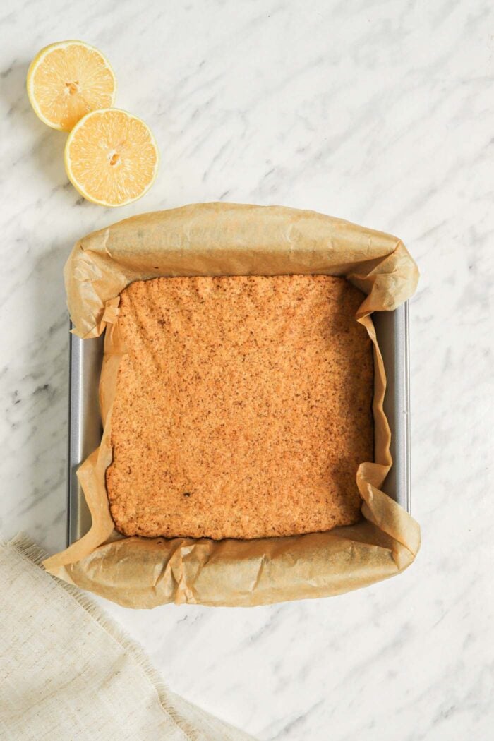 A golden brown baked crust in a square baking dish lined with parchment paper.