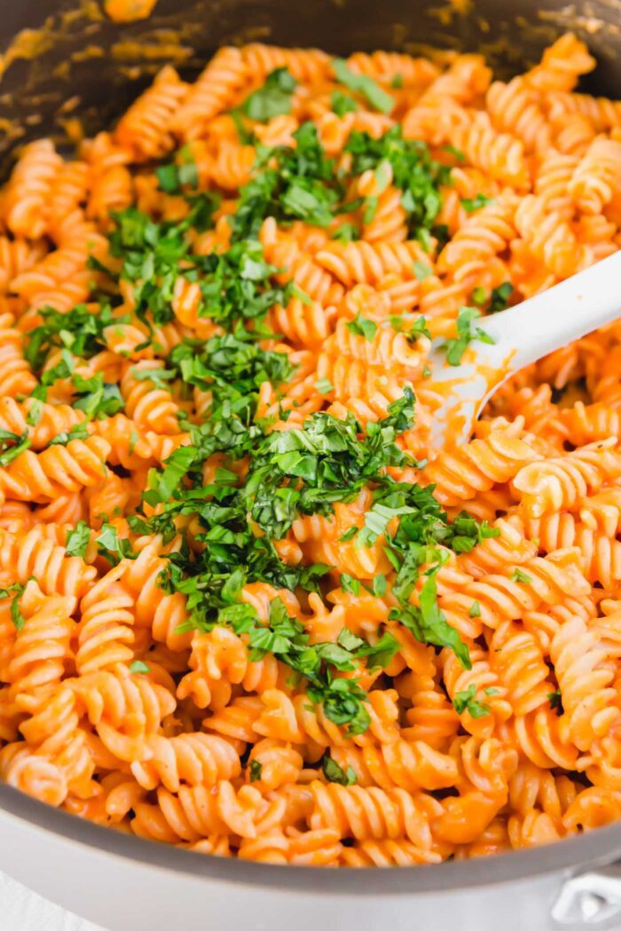 Roasted red pepper pasta topped with fresh parsley in a larges skillet.