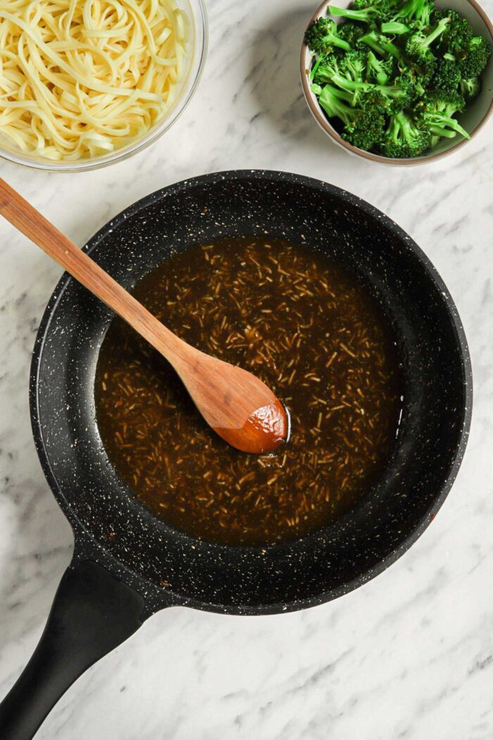 A sesame sauce with grated ginger and garlic in it cooking in a skillet.