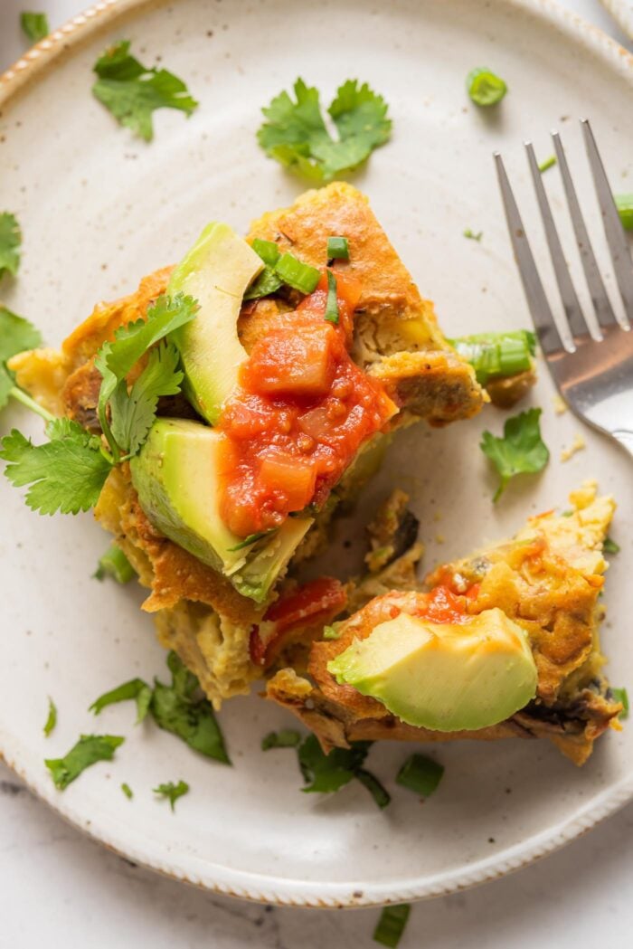 Overhead view of a square of vegan breakfast potato casserole topped with avocado and salsa.