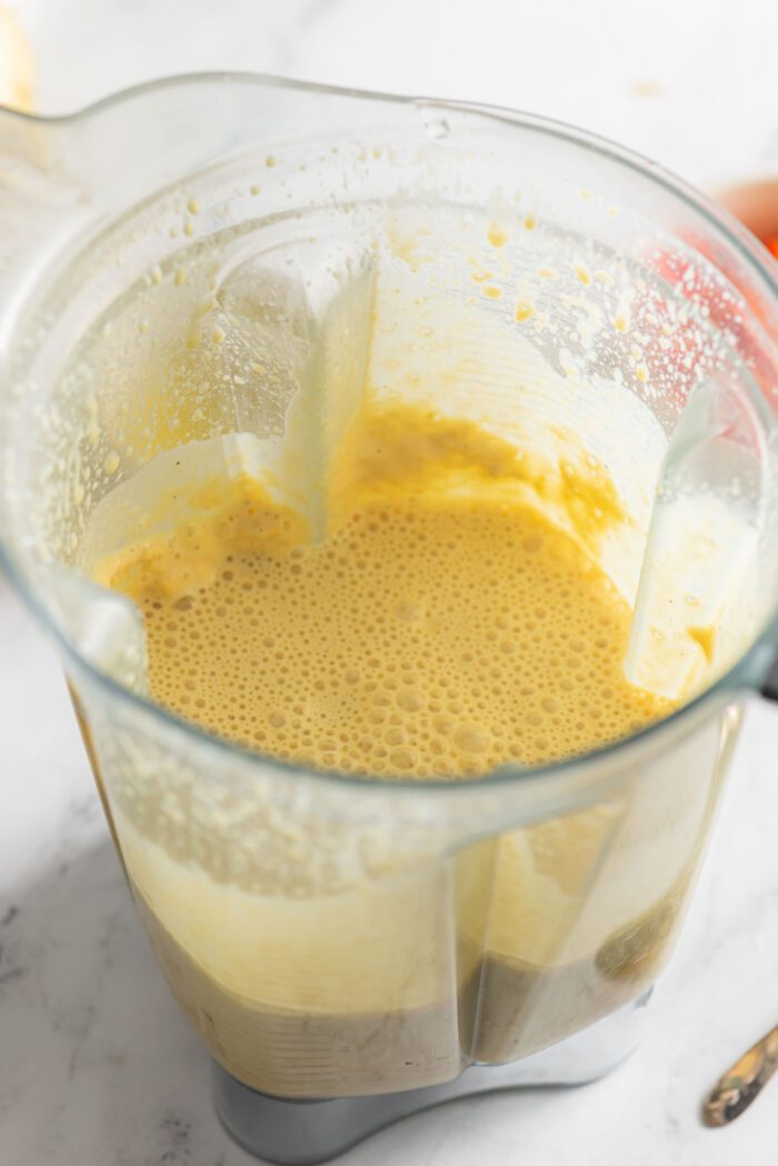 A yellow vegan egg batter made from tofu and chickpea flour in a blender container.