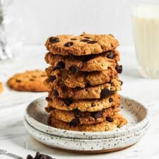 Stack of almond flour chocolate chip cookies on a small plate with a glass of milk in the background.