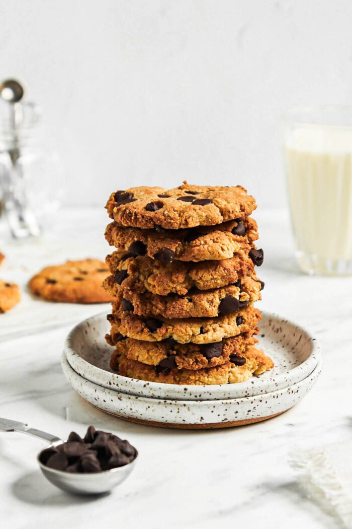 Stack of almond flour chocolate chip cookies on a small plate with a glass of milk in the background.