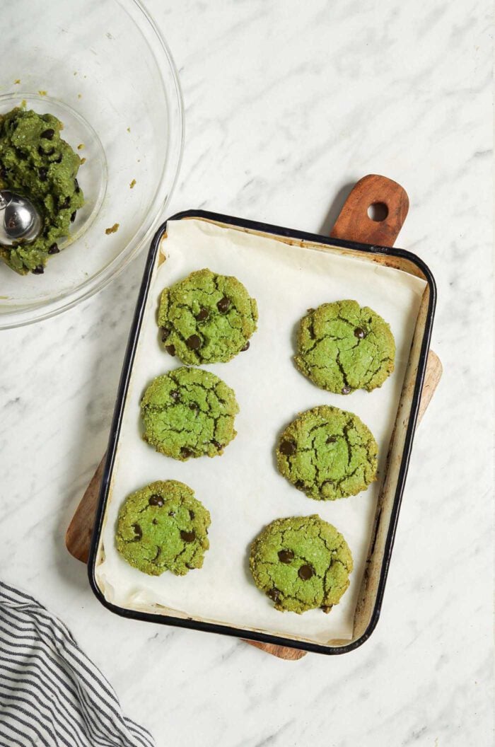 6 green vegan matcha cookies on a baking tray.