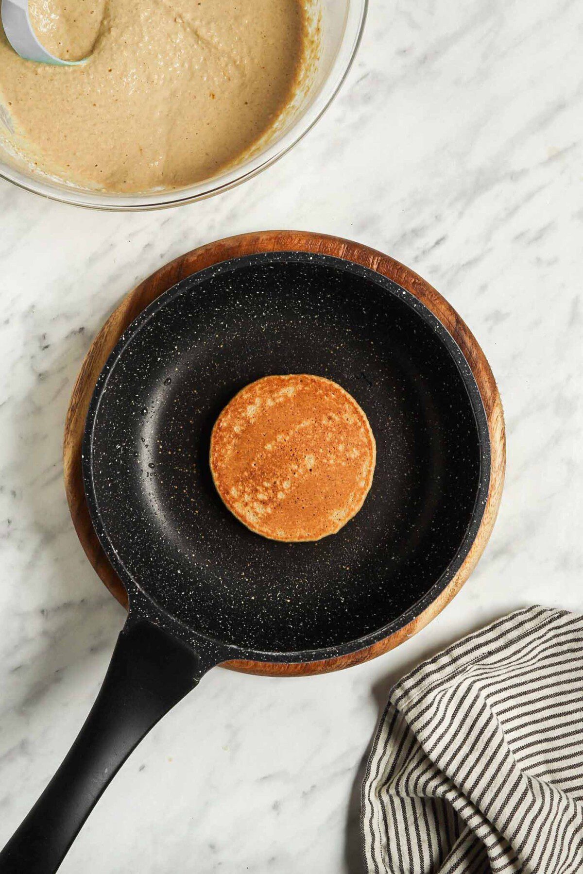 A cooked, small brown pancake in a small skillet.