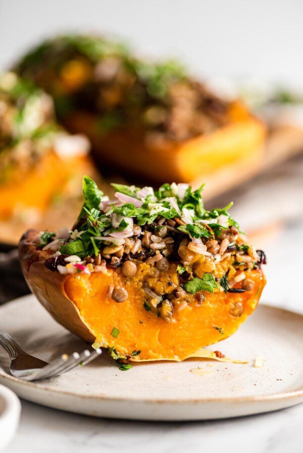 A wedge of sliced stuffed butternut squash on a plate with a fork.